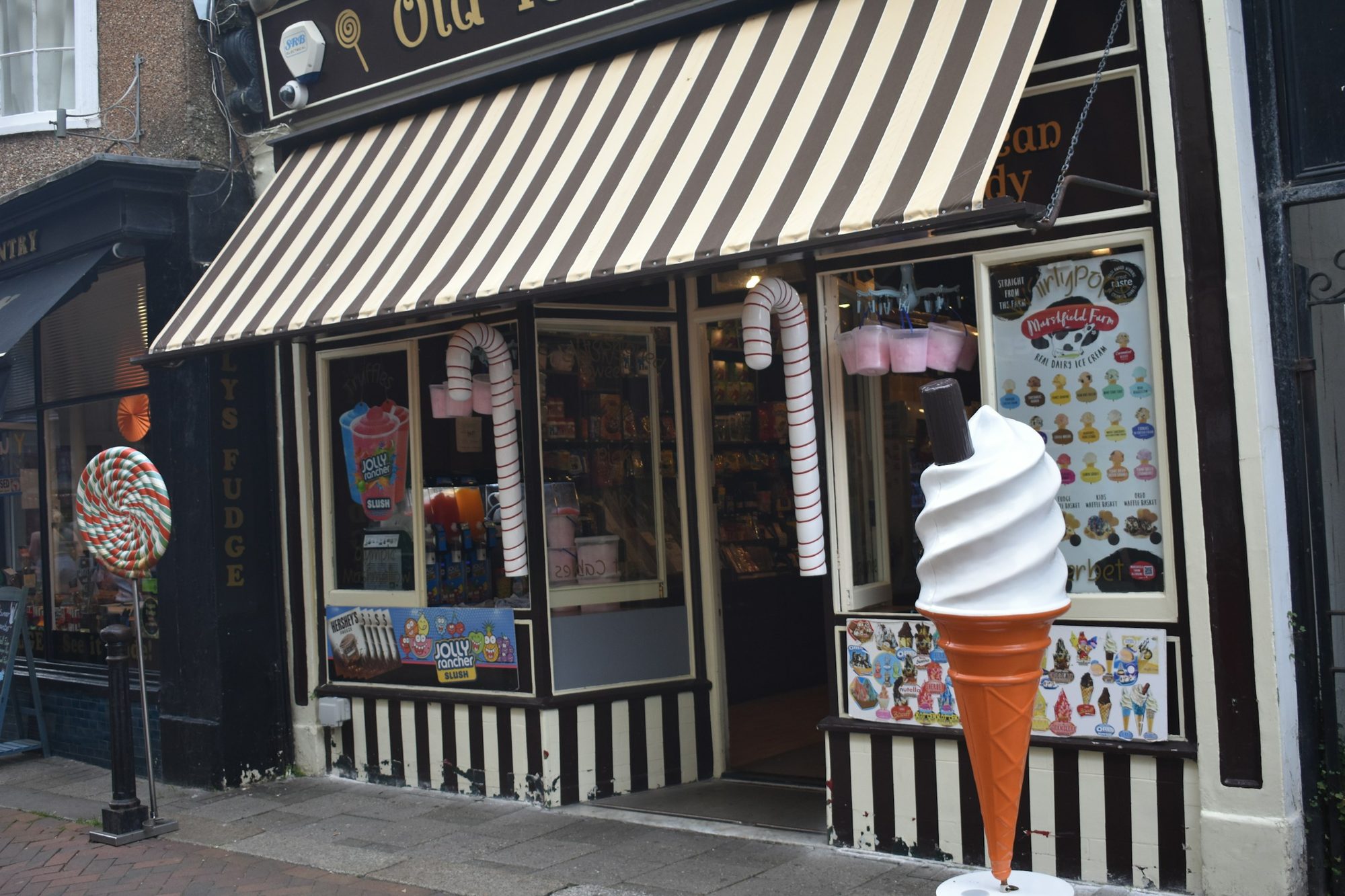 La devanture d'un glacier en rue, store rayé et vitrine garnie, par une belle journée