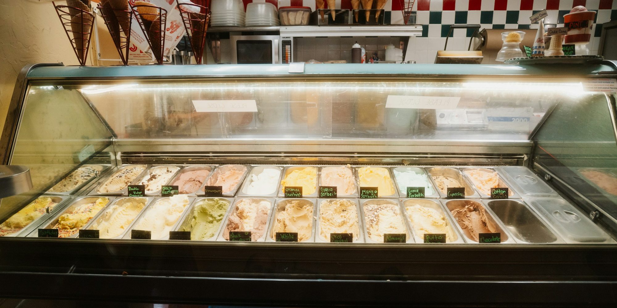 La vitrine réfrigérée d'un glacier, garnie de bacs de gelato colorés et étiquetés